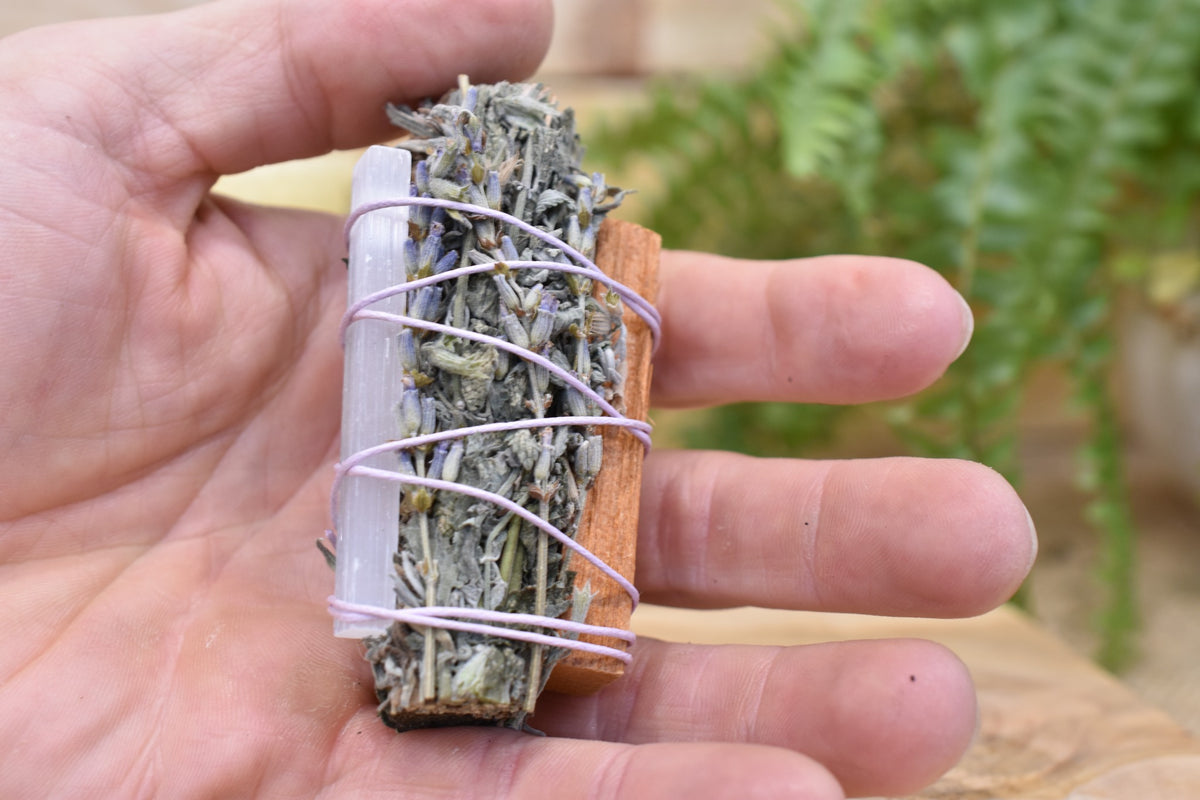 Moon Ward Wand naturally held, showing dried herbs, Palo Santo and selenite