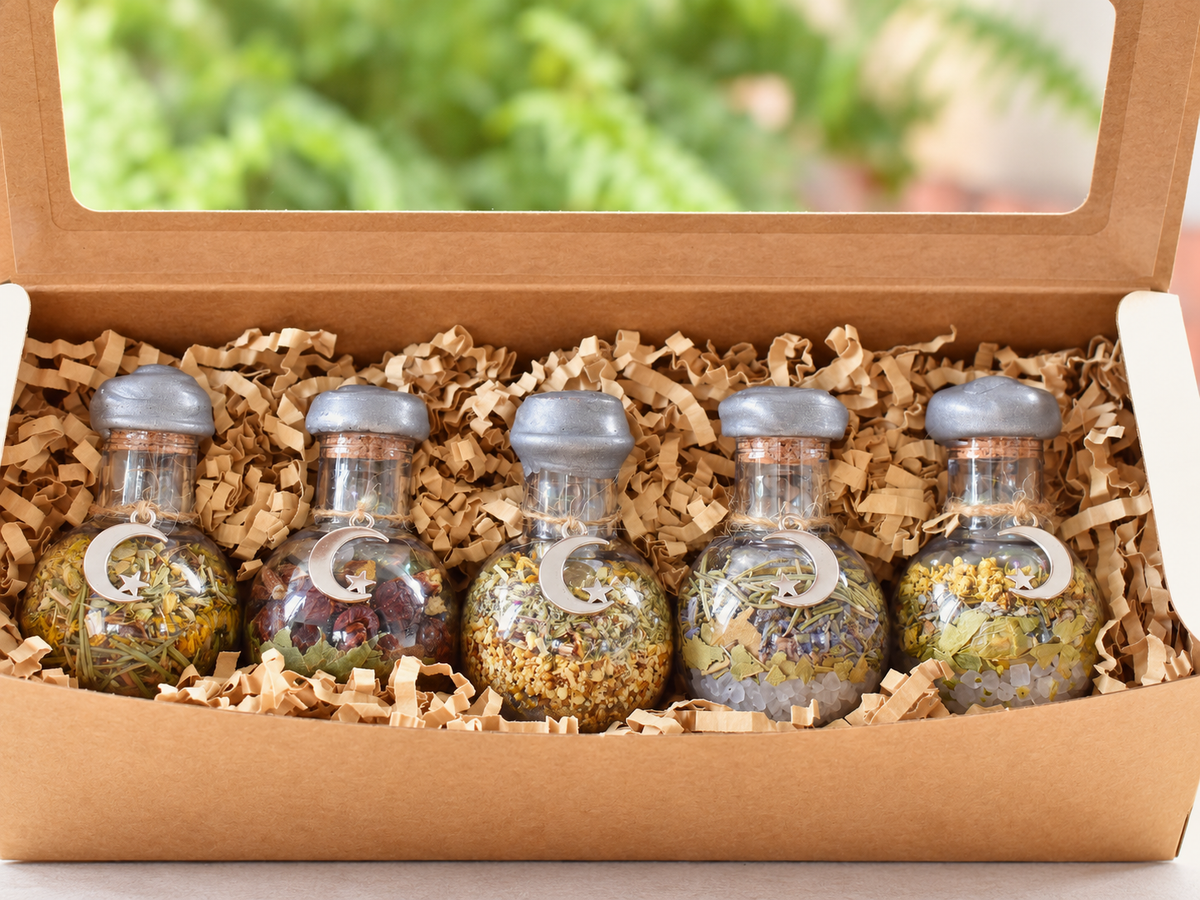 Close-up of handcrafted Moon Collection jars showing herbs, stones, twine and crescent charms.