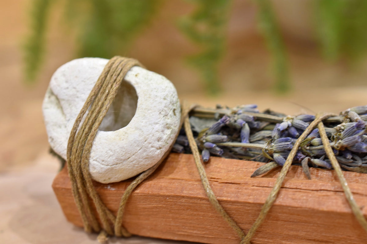 Guardian’s Wand close-up showing hand-bound dried botanicals and Witch’s Window hag stone